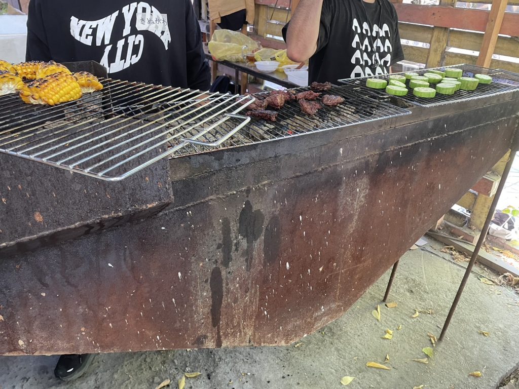 キルギス日本人会のBBQで肉とトウモロコシが焼かれている様子です。
